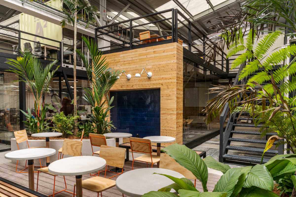 Patio interior de NOI Coworking con mesas, sillas, plantas y luz natural